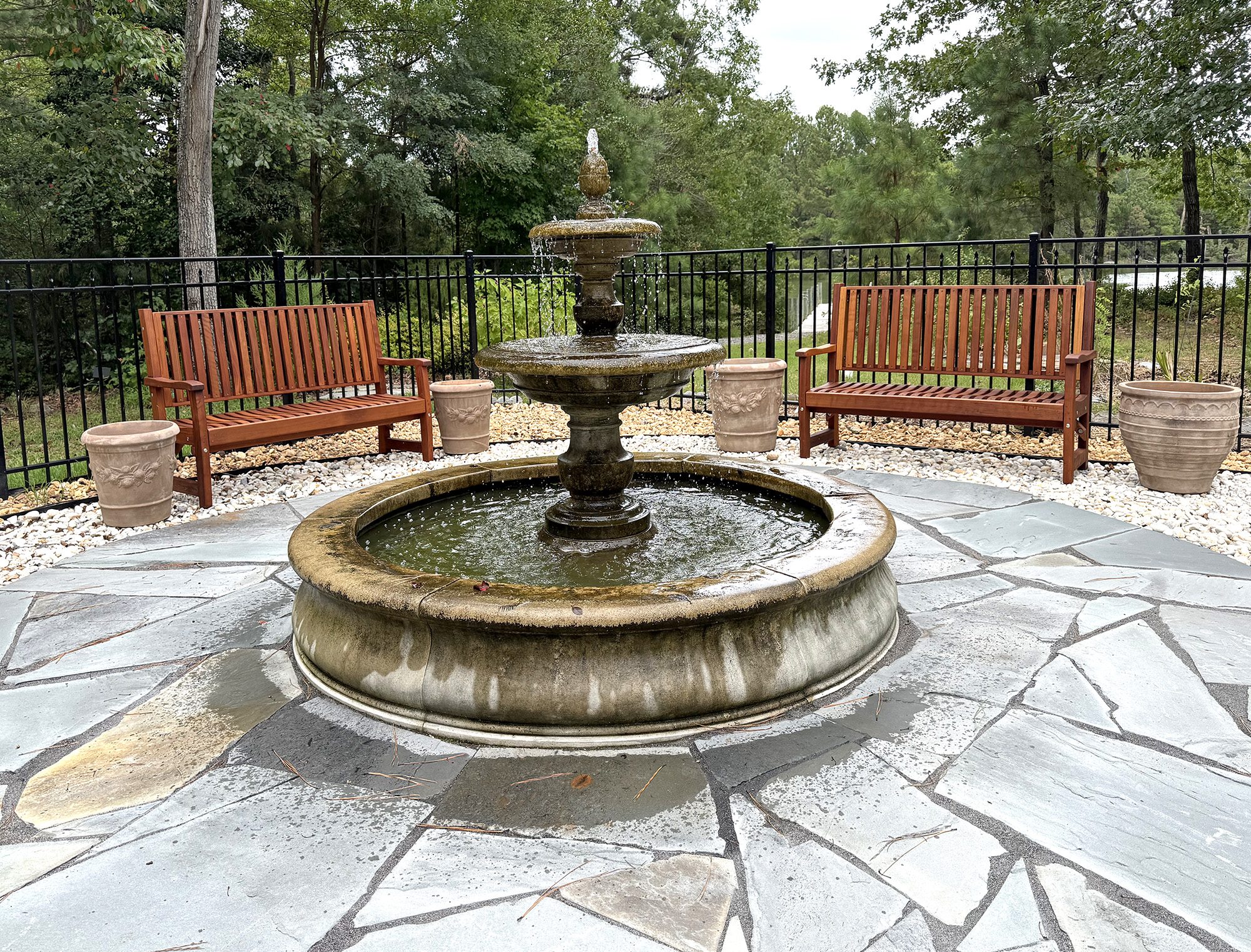Redwood garden benches around a stone fountain