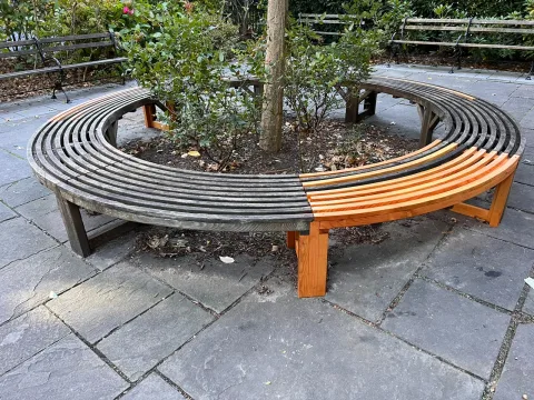 The round tree bench rebuilt, with new redwood slats and legs next to the weathered original wood
