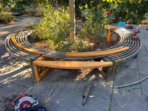 New redwood legs and seat slats being fitted into the old round tree bench
