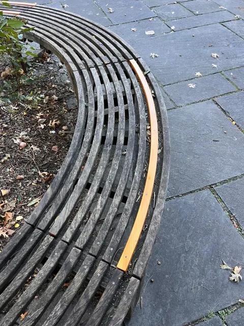 One new curved redwood slat replacing a broken one in the old bench