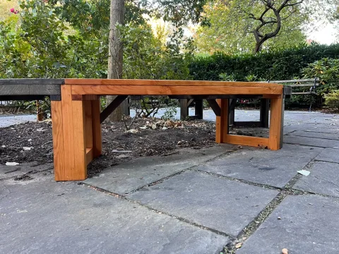 A new redwood bench section with new legs, joined to the old weathered bench