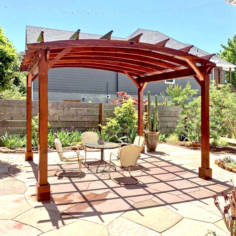 Arched Open Sky Pergolas (Options: 12' L x 14' Arc W, California Redwood, 1 Electrical Wiring Trim, 4 Post Anchor Kit for Concrete, No Ceiling Fan Base, No Privacy Panels, No Curtain Rods, 9.5' Post Height, Transparent Premium Sealant). Custom decorative steel shading added by customer. Photo was taken one year after installation. Photo Courtesy of K. Cates of Oajland, California. Arched Open Sky Pergolas (Options: 12' L x 14' Arc W, California Redwood, 1 Electrical Wiring Trim, 4 Post Anchor Kit for Concrete, No Ceiling Fan Base, No Privacy Panels, No Curtain Rods, 9.5' Post Height, Transparent Premium Sealant). Custom decorative steel shading added by customer. Photo was taken one year after installation. Photo Courtesy of K. Cates of Oajland, California.
