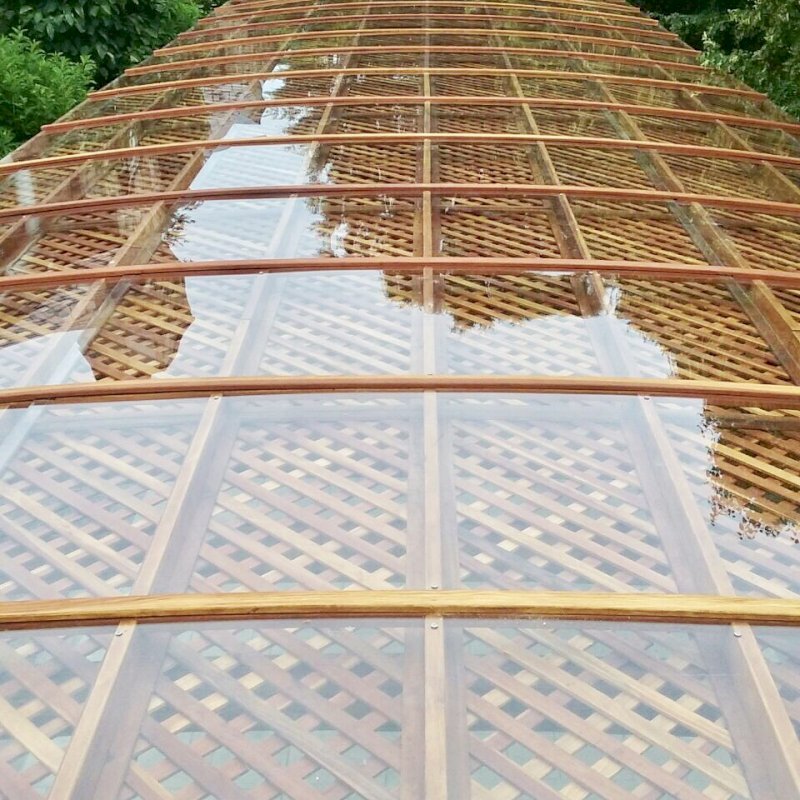 Arched Pergola Kit (Options: 74' L x 18.5' Arc W, Mature Redwood, Electrical Wiring Trim for 1 Post, 10 Post Anchor Kit for Concrete, 2 Ceiling Fan Bases, No Privacy Panels, No Curtain Rods, with Transparent Rain Guard, 9' Post Height, Transparent Premium Sealant). Photo Courtesy of H. Mitchell of The Plains, VA. Arched Pergola Kit (Options: 74' L x 18.5' Arc W, Mature Redwood, Electrical Wiring Trim for 1 Post, 10 Post Anchor Kit for Concrete, 2 Ceiling Fan Bases, No Privacy Panels, No Curtain Rods, with Transparent Rain Guard, 9' Post Height, Transparent Premium Sealant). Photo Courtesy of H. Mitchell of The Plains, VA.