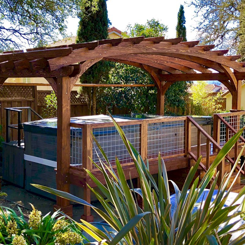 Custom Arched Pergola Kit (Options: 12' L x 22' Arc W, Douglas-fir, Unattached, Electrical Wiring Trim Kit for 1 Post, Arched Roof with Lattice Panels and Acrylic Sheets Centered, 4 Post Anchor Kit for Stone, No Ceiling Fan Base, No Privacy Panels, No Curtain Rods, 9' Post Height, Coffee-Stain Premium Sealant) with Custom Deck and Stairs by Custom Request. Photo Courtesy of Steve & Heidi Jones of Windsor, CA. Custom Arched Pergola Kit (Options: 12' L x 22' Arc W, Douglas-fir, Unattached, Electrical Wiring Trim Kit for 1 Post, Arched Roof with Lattice Panels and Acrylic Sheets Centered, 4 Post Anchor Kit for Stone, No Ceiling Fan Base, No Privacy Panels, No Curtain Rods, 9' Post Height, Coffee-Stain Premium Sealant) with Custom Deck and Stairs by Custom Request. Photo Courtesy of Steve & Heidi Jones of Windsor, CA.