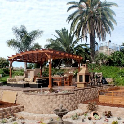 Arched Pergola Kits (Options: 16' L x 20' Arc W, California Redwood, No Electrical Wiring Trim, 4-Post Anchor Kit for Stone, No Ceiling Fan Base, No Privacy Panel, No curtain Rods, 9' Post Height, Transparent Premium Sealant). 12' Patio Table w/Benches & Ruth Chairs Also Shown. Photo courtesy of Mr. M. Tomacelli of Fallbrook, CA.