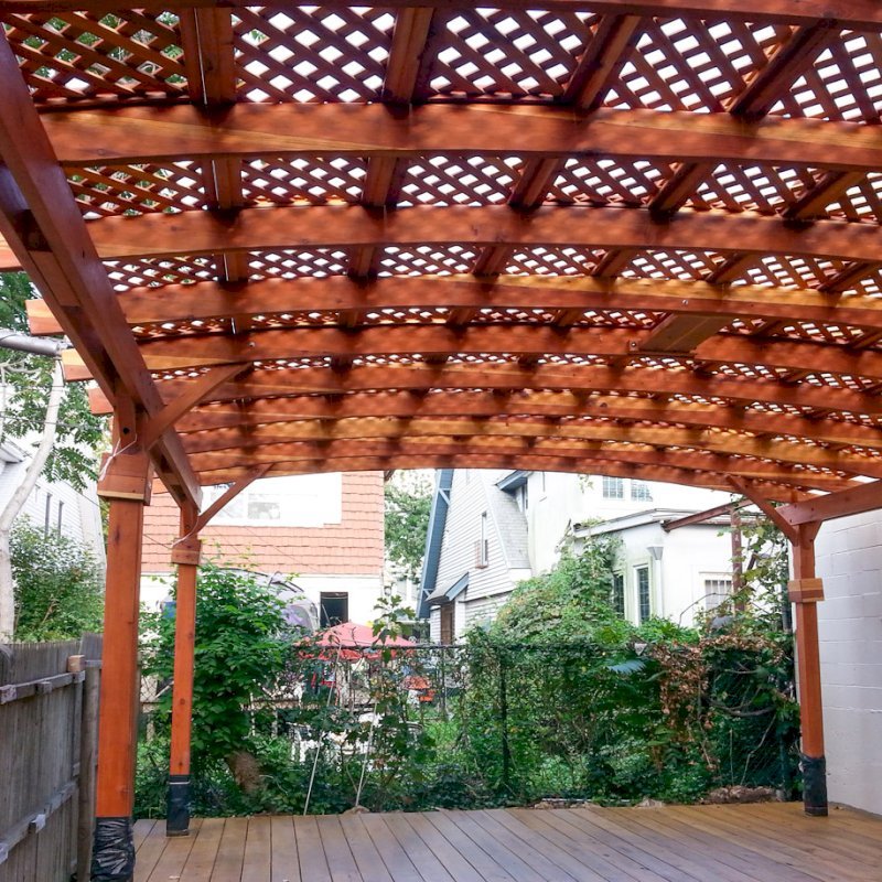Arched Pergola Kits (Options: 25' L x 20' Arc W, California Redwood, Unattached, No Electrical Wiring Trim, Arched Roof with Lattice Panels, 6 Post Anchor Kit for Stone, with Ceiling Fan Base, No Privacy Panels, No Curtain Rods, Transparent Premium Sealant). Note: Photo shows roof detail of pergola still under construction (note trim kit boxes set near top of posts and plastic wrap around anchoring hardware at base of posts). Photo Courtesy of Mr. Ami Liani of Brooklyn, NY. Arched Pergola Kits (Options: 25' L x 20' Arc W, California Redwood, Unattached, No Electrical Wiring Trim, Arched Roof with Lattice Panels, 6 Post Anchor Kit for Stone, with Ceiling Fan Base, No Privacy Panels, No Curtain Rods, Transparent Premium Sealant). Note: Photo shows roof detail of pergola still under construction (note trim kit boxes set near top of posts and plastic wrap around anchoring hardware at base of posts). Photo Courtesy of Mr. Ami Liani of Brooklyn, NY.
