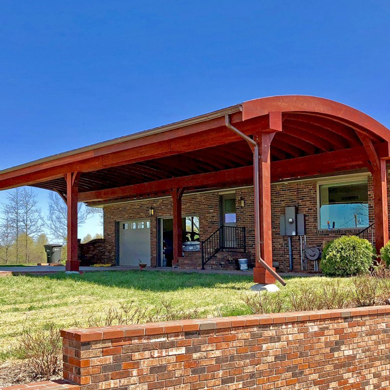 Custom Arched Thick Timber Pavilion (Options: 55' L x 22' Arc W, California Redwood, No Electrical Wiring Trim, 6 Post Anchor Kit for Gale-Wind, 2 Ceiling Fan Bases, No Privacy Panel, No Curtain Rods, 10ft H, Cherry Stain Premium Sealant) Support timbers covered by custom request. Photo also shows a Round Picnic Table. Photo Courtesy of J. Hartmann of Pittsburg, KS. Custom Arched Thick Timber Pavilion (Options: 55' L x 22' Arc W, California Redwood, No Electrical Wiring Trim, 6 Post Anchor Kit for Gale-Wind, 2 Ceiling Fan Bases, No Privacy Panel, No Curtain Rods, 10ft H, Cherry Stain Premium Sealant) Support timbers covered by custom request. Photo also shows a Round Picnic Table. Photo Courtesy of J. Hartmann of Pittsburg, KS.
