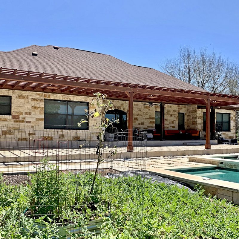Custom Attached Garden Pergola (Options: 53' x 12', California Redwood, Open Roof with Slats at 12", Rafters at 18", 3-Post Anchor Kit for Concrete, 3 Ceiling Fan Bases, Coffee-Stain Premium Sealant). Ledger Board Attached to Wood House Fascia on 53' Side, and Steel Plate Used to Attach Dual Supports to Masonry House Wall. Photo Courtesy of S. Slawson of Buda, Texas. Custom Attached Garden Pergola (Options: 53' x 12', California Redwood, Open Roof with Slats at 12", Rafters at 18", 3-Post Anchor Kit for Concrete, 3 Ceiling Fan Bases, Coffee-Stain Premium Sealant). Ledger Board Attached to Wood House Fascia on 53' Side, and Steel Plate Used to Attach Dual Supports to Masonry House Wall. Photo Courtesy of S. Slawson of Buda, Texas.