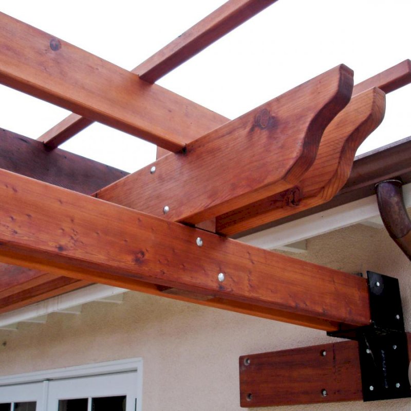 Some attached pergolas cannot be secured with a ledger board. In some instances, we build custom steel anchors to get the job done like shown here. Photo also highlights the extensive notching and finishing work that goes into each timber of our Kits. Some attached pergolas cannot be secured with a ledger board. In some instances, we build custom steel anchors to get the job done like shown here. Photo also highlights the extensive notching and finishing work that goes into each timber of our Kits.