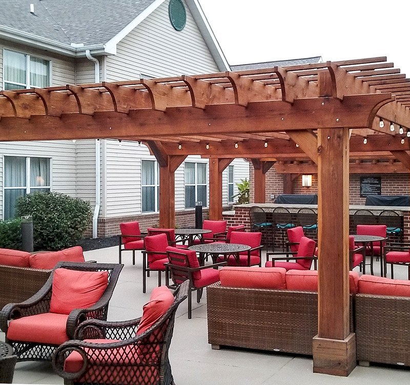 Custom Wooden Fat Timber Pergola (Options: 20' x 20', California Redwood, Electrical Wiring Trim for 1 Post, Open Roof with Rafters at 18", Slats at 12", 4-Post Anchor Kit for Concrete, No Ceiling Fan Bases, No Privacy Panels, No Curtain Rods, Transparent Premium Sealant). Thicker Lumber by Custom Request, 2 x 12 Rafters & Supports, 10 x10 Posts. Photo Courtesy of Homewood Suites by Hilton, Mechanicsburg, PA. Custom Wooden Fat Timber Pergola (Options: 20' x 20', California Redwood, Electrical Wiring Trim for 1 Post, Open Roof with Rafters at 18", Slats at 12", 4-Post Anchor Kit for Concrete, No Ceiling Fan Bases, No Privacy Panels, No Curtain Rods, Transparent Premium Sealant). Thicker Lumber by Custom Request, 2 x 12 Rafters & Supports, 10 x10 Posts. Photo Courtesy of Homewood Suites by Hilton, Mechanicsburg, PA.