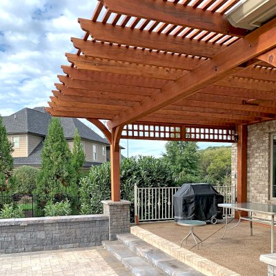 Custom Wooden Fat Timber Pergola (Options: 21' x 18', Mature Redwood, 1 Custom Lattice Privacy Panel, 1 Ceiling Fan Base, Transparent Premium Sealant). This customized attached pergola was built to fit around a low roof with an extended overhang and posts up against the house to meet the customer's vision perfectly. Photo Courtesy of B. McAdams of Farragut, Tennessee.