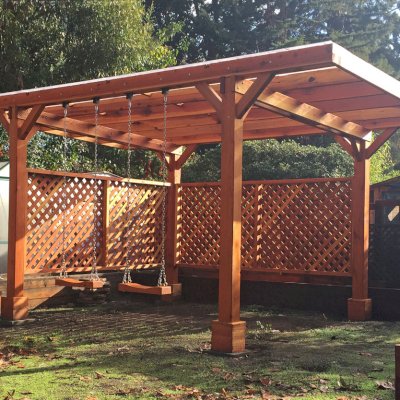 Custom Wooden Pergola (Options: 18' x 15', California Redwood, No Electrical Wiring Trim, Widthwise Roof Supports TImbers, 4-Post Anchor Kit for Stone, 2 Privacy Panels, No Curtain Rods, Roof with a Slope, Transparent Sealant) with 2 Rory's Swing Seats, Added by Custom Request. Customer Added Lexan Panels. Photo Courtesy of Tina Phi of Palo Alto, CA.