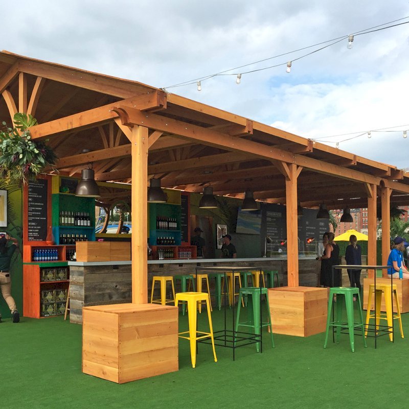 Rio on the Hudson: Olympic Village in NYC. 2 Del Norte Outdoor Kitchen Pavilions (Options: 25' L x 20' W, Douglas-fir, We used 2' x 2' x 2' Concrete Blocks to Anchor the Structure Because it is a Temporary Installation, Covered the Concrete Blocks with Wooden Boxes, No Ceiling Fan Base, Transparent Premium Sealant). Photo Courtesy of A. Fisher of New York, NY. Rio on the Hudson: Olympic Village in NYC. 2 Del Norte Outdoor Kitchen Pavilions (Options: 25' L x 20' W, Douglas-fir, We used 2' x 2' x 2' Concrete Blocks to Anchor the Structure Because it is a Temporary Installation, Covered the Concrete Blocks with Wooden Boxes, No Ceiling Fan Base, Transparent Premium Sealant). Photo Courtesy of A. Fisher of New York, NY.