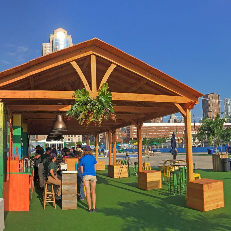 Rio on the Hudson: Olympic Village in NYC. 2 Del Norte Outdoor Kitchen Pavilions (Options: 25' L x 20' W, Douglas-fir, We used 2' x 2' x 2' Concrete Blocks to Anchor the Structure Because it is a Temporary Installation, Covered the Concrete Blocks with Wooden Boxes, No Ceiling Fan Base, Transparent Premium Sealant). Photo Courtesy of A. Fisher of New York, NY. Rio on the Hudson: Olympic Village in NYC. 2 Del Norte Outdoor Kitchen Pavilions (Options: 25' L x 20' W, Douglas-fir, We used 2' x 2' x 2' Concrete Blocks to Anchor the Structure Because it is a Temporary Installation, Covered the Concrete Blocks with Wooden Boxes, No Ceiling Fan Base, Transparent Premium Sealant). Photo Courtesy of A. Fisher of New York, NY.
