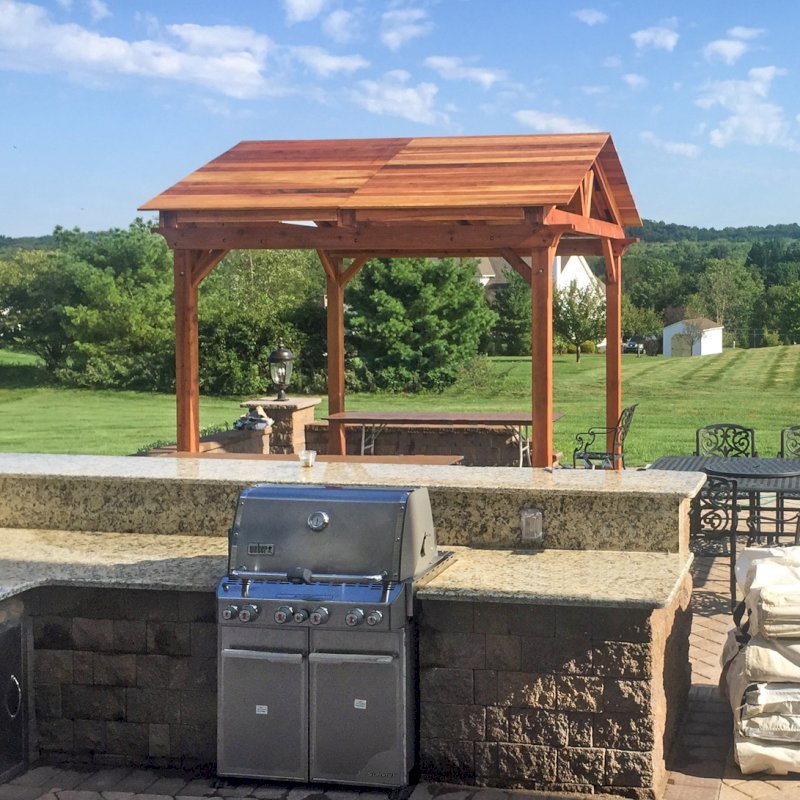 Del Norte Outdoor Kitchen Pavilion (Options: 12' L x 12' W, California Redwood, Unattached, 4-Post Kit for Concrete, Electrical Wiring Trim for 1 Post, 9' Posts, No Ceiling Fan Base, No Privacy Panels, No Curtain Rods, Transparent Premium Sealant). Photo Courtesy of Manjit Guleria of Pennington, NJ. Del Norte Outdoor Kitchen Pavilion (Options: 12' L x 12' W, California Redwood, Unattached, 4-Post Kit for Concrete, Electrical Wiring Trim for 1 Post, 9' Posts, No Ceiling Fan Base, No Privacy Panels, No Curtain Rods, Transparent Premium Sealant). Photo Courtesy of Manjit Guleria of Pennington, NJ.