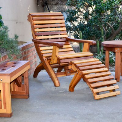 Ensenada Wood Easy Chair (Options: Standard Size, California Redwood, No Cushion, Ottoman, Transparent Premium Sealant). Photo also shows a round side table and a lighthouse bench. 