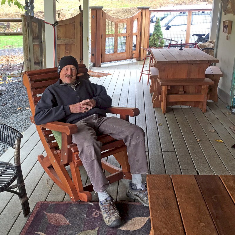 Ensenada Rocking Chair (Options: Standard Width, Old-Growth Redwood, No Cushion,Transparent Premium Sealant). Photo also shows a Trestle Table Set in background. Photo Courtesy of R. Bogardus of Jacksonville, OR. Ensenada Rocking Chair (Options: Standard Width, Old-Growth Redwood, No Cushion,Transparent Premium Sealant). Photo also shows a Trestle Table Set in background. Photo Courtesy of R. Bogardus of Jacksonville, OR.