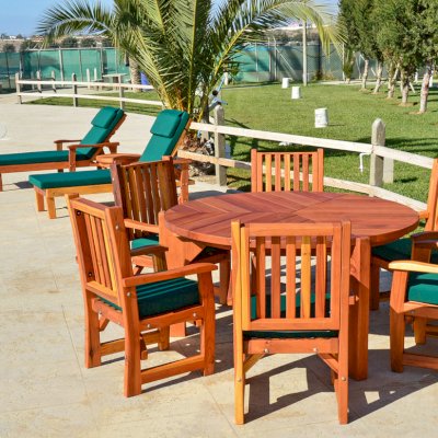 Lisa's Retro Outdoor Patio Table (Options: 5' Diameter, Chairs, California Redwood, with 6 Ruth Armchairs with Forest Green Cushions, Standard Tabletop, No Lazy Susan, No Umbrella Hole, Transparent Premium Sealant). Photo Also Shows 2 Pool Loungers. 