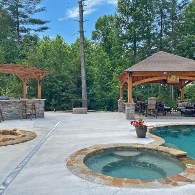 Marin Outdoor Kitchen Pergola (Options: 14' L x 15' Arc W, Douglas-fir, Unattached, 1 Post Electrical Wiring Trim, 4-Post Anchor Kit for High-Wind, No Ceiling Fan Base, No Privacy, No Curtain Rods, 9.5 ft Post Height (posts wrapped with masonry), Transparent Premium Sealant). Photo Also Shows a Loreto Pavilion. Photo Courtesy of Bill & Lori O’Mara of Marion, North Carolina.