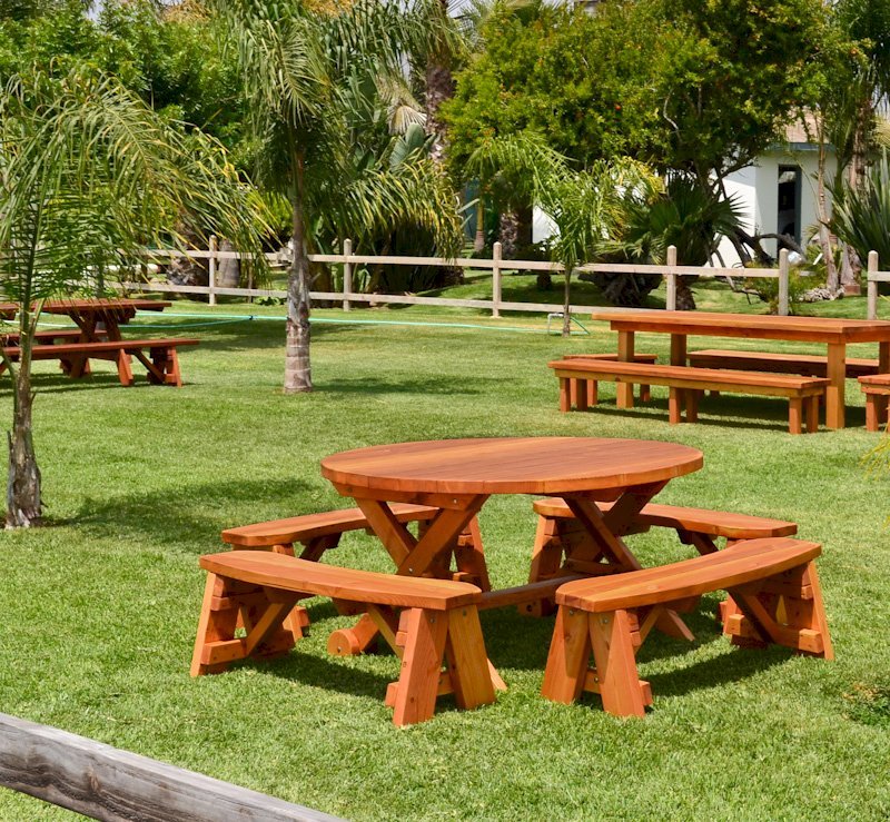 Round Wood Picnic Table with Wheels (Options: 5' Diameter, Unattached Benches, Redwood, Round Picnic Benches, Standard Tabletop, No Lazy Susan, No Umbrella Hole, Transparent Premium Sealant). Rectangular Picnic Table and Rectangular Patio Table in background. Round Wood Picnic Table with Wheels (Options: 5' Diameter, Unattached Benches, Redwood, Round Picnic Benches, Standard Tabletop, No Lazy Susan, No Umbrella Hole, Transparent Premium Sealant). Rectangular Picnic Table and Rectangular Patio Table in background.