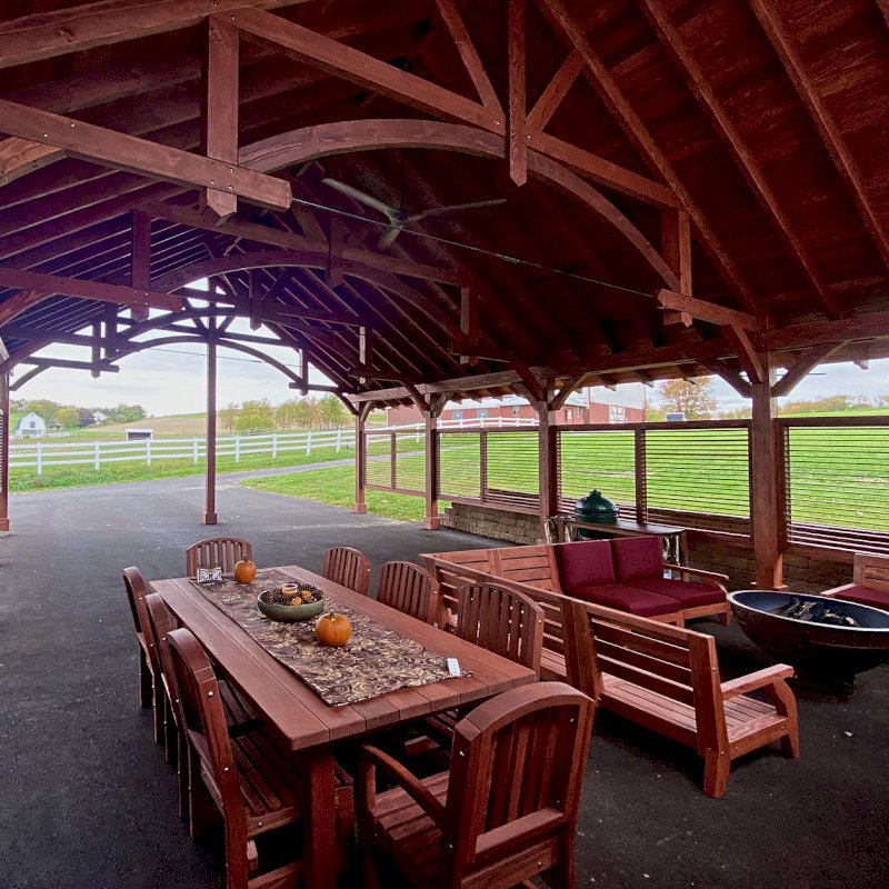 San Francisco Redwood Patio Table Under a Cardinal's Nest Pavilion (Options: 8' L, 48" W Tabletop, 2 Armchairs + Side Chairs, Douglas-fir, Luna Chairs, Standard Tabletop, Slightly Rounded Corners, No Umbrella Hole, Transparent Premium Sealant). Photo also shows some Custom Kari's Chairs. Photo Courtesy of S. Steckman of East Liverpool, Ohio. San Francisco Redwood Patio Table Under a Cardinal's Nest Pavilion (Options: 8' L, 48" W Tabletop, 2 Armchairs + Side Chairs, Douglas-fir, Luna Chairs, Standard Tabletop, Slightly Rounded Corners, No Umbrella Hole, Transparent Premium Sealant). Photo also shows some Custom Kari's Chairs. Photo Courtesy of S. Steckman of East Liverpool, Ohio.