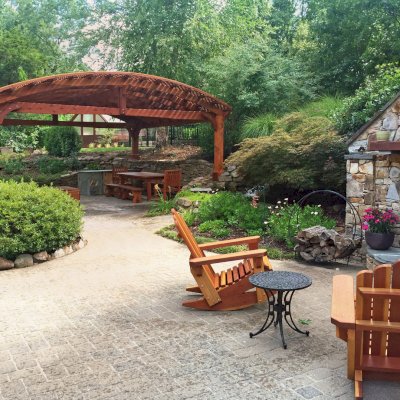 San Francisco Redwood Patio Table (Options: 8' L, 40 1/4" W Tabletop, Benches & End Armchairs, Mature Redwood, Trestle Bench Design, Ruth Chair Design, No Cushions, Standard Tabletop, Slightly Rounded Corners, No Umbrella Hole, Transparent Premium Sealant). Photo also shows a Viking Pergola and two Adirondack Rocking Chairs. Photo Courtesy of Diego B. of Huntsville, AL.