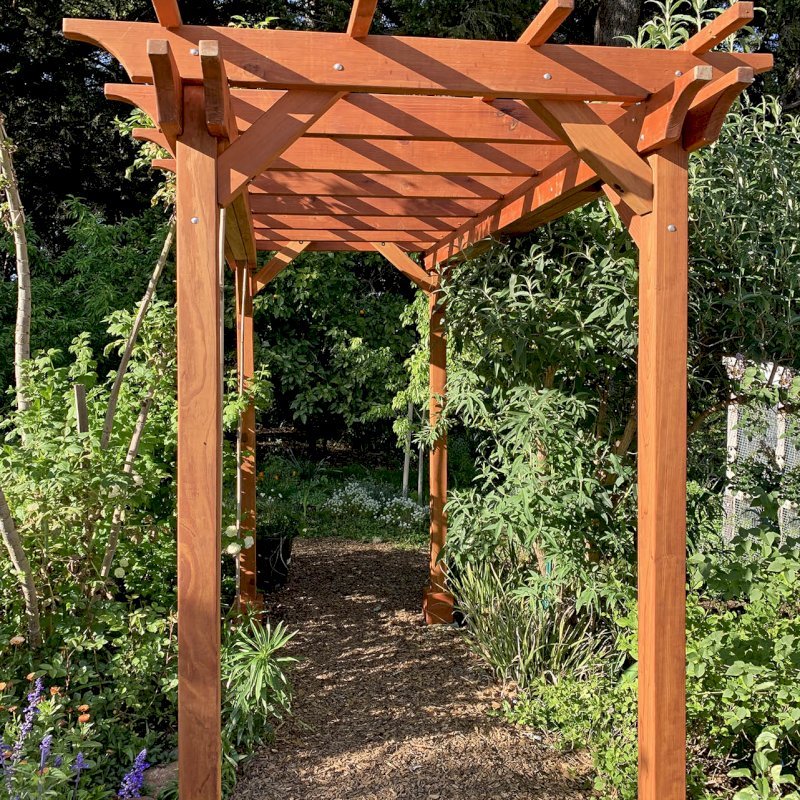 Small Garden Pergola Kit (Options: 12' L x 6' W, 2 x 6's Supports and Rafters by Custom Request, No Privacy Panels, Mature Redwood, 9' Post height, 4-Post Anchor Kit for Concrete, No Curtain Rods, No Decorative Trims, Transparent Premium Sealant). Photo Courtesy of R. Lilley of Guerneville, California. Small Garden Pergola Kit (Options: 12' L x 6' W, 2 x 6's Supports and Rafters by Custom Request, No Privacy Panels, Mature Redwood, 9' Post height, 4-Post Anchor Kit for Concrete, No Curtain Rods, No Decorative Trims, Transparent Premium Sealant). Photo Courtesy of R. Lilley of Guerneville, California.