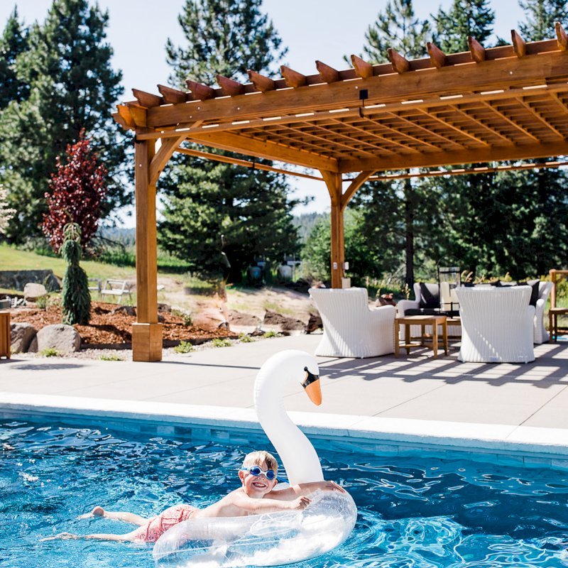 The Montvale Pergola (Options: 22' x 22', Mature Redwood, Post Anchoring for Concrete, Electrical Wiring Trim Kit for 4 Posts, No Ceiling Fan Base, 4 Curtain Rods, No Privacy Panels, 10' Post, Transparent Premium Sealant). Photo Courtesy of J. Scott of Coeur deline, Idaho. The Montvale Pergola (Options: 22' x 22', Mature Redwood, Post Anchoring for Concrete, Electrical Wiring Trim Kit for 4 Posts, No Ceiling Fan Base, 4 Curtain Rods, No Privacy Panels, 10' Post, Transparent Premium Sealant). Photo Courtesy of J. Scott of Coeur deline, Idaho.