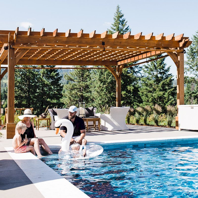 The Montvale Pergola (Options: 22' x 22', Mature Redwood, Post Anchoring for Concrete, Electrical Wiring Trim Kit for 4 Posts, No Ceiling Fan Base, 4 Curtain Rods, No Privacy Panels, 10' Post, Transparent Premium Sealant). Photo Courtesy of J. Scott of Coeur deline, Idaho. The Montvale Pergola (Options: 22' x 22', Mature Redwood, Post Anchoring for Concrete, Electrical Wiring Trim Kit for 4 Posts, No Ceiling Fan Base, 4 Curtain Rods, No Privacy Panels, 10' Post, Transparent Premium Sealant). Photo Courtesy of J. Scott of Coeur deline, Idaho.