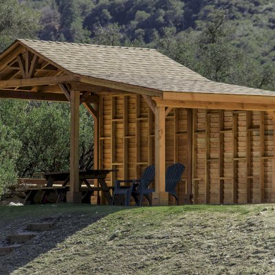 Sunset Patio Pavilion Attached to a 12' x 12' Del Norte Pavilion (Options: 9' x 12', Douglas-fir, No Ceiling Fan Base, No Electrical Wiring Trim Kit, 2-Post Anchor Kit for High-Wind, with Custom Solid Wall, Transparent Premium Sealant). Photo Courtesy of J. Randall of Warner Springs, CA.