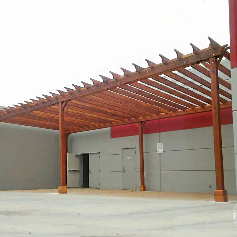 The Traditional Wooden Garden Pergola (Options: 42' L x 18' W, California Redwood, No Electrical Wiring Trim, Open Roof with Rafters at 18", Lengthwise Roof Support Timbers, 6-Post Anchor Kit for Concrete, No Ceiling Fan Base, No Privacy Panels, No Curtain Rods, 12' Post Height, Transparent Premium Sealant). This order was customized to not have the standard 2x2 slats above and perpendicular to the main 2x6 rafters. Instead, we added blocking between the 2x6 slats as can be seen above the main support timber headers. Photo Courtesy of J. Porter of Moreno Valley, CA. The Traditional Wooden Garden Pergola (Options: 42' L x 18' W, California Redwood, No Electrical Wiring Trim, Open Roof with Rafters at 18", Lengthwise Roof Support Timbers, 6-Post Anchor Kit for Concrete, No Ceiling Fan Base, No Privacy Panels, No Curtain Rods, 12' Post Height, Transparent Premium Sealant). This order was customized to not have the standard 2x2 slats above and perpendicular to the main 2x6 rafters. Instead, we added blocking between the 2x6 slats as can be seen above the main support timber headers. Photo Courtesy of J. Porter of Moreno Valley, CA.