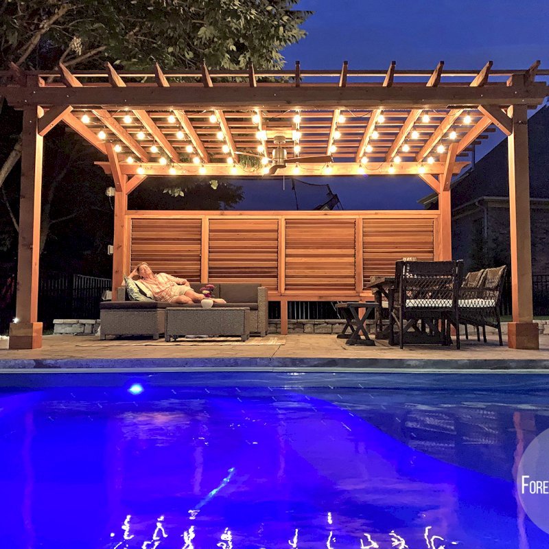 The Traditional Wooden Garden Pergola (Options: 18' L x 12' W, California Redwood, 1 Electrical Wiring Trim, Open Roof with Slats at 12", Rafters at 18", Lengthwise Roof Support Timbers, 4-Post Anchor Kit for Concrete, No Ceiling Fan Base, 1 Louver Privacy Panel Half Height Without Wall, 1 Curtain Rods, 9' Post Height, Transparent Premium Sealant). Photo Courtesy of Sasha Antskaitis of Louisville, Kentucky. The Traditional Wooden Garden Pergola (Options: 18' L x 12' W, California Redwood, 1 Electrical Wiring Trim, Open Roof with Slats at 12", Rafters at 18", Lengthwise Roof Support Timbers, 4-Post Anchor Kit for Concrete, No Ceiling Fan Base, 1 Louver Privacy Panel Half Height Without Wall, 1 Curtain Rods, 9' Post Height, Transparent Premium Sealant). Photo Courtesy of Sasha Antskaitis of Louisville, Kentucky.