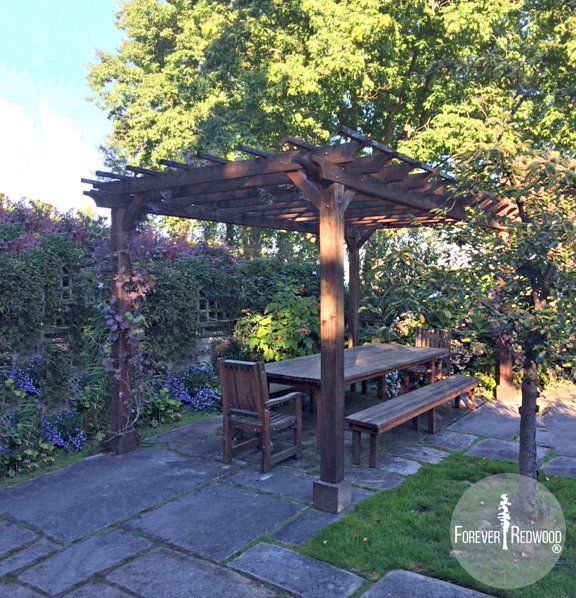 The Traditional Wooden Garden Pergola built in 2012 and photographed in 2016 showing how California Redwood's finish ages if not retreated, (Options: 18' L x 11' W, Mature Redwood, No Electrical Wiring Trim, Open Roof with Slats at 18", Rafters at 18", 4-Post Anchor Kit for Concrete, 9' Post Height, Transparent Premium Sealant). Photo Also Shows a San Francisco Patio Table Set. Courtesy of C. Moseley of Seattle, Washington. The Traditional Wooden Garden Pergola built in 2012 and photographed in 2016 showing how California Redwood's finish ages if not retreated, (Options: 18' L x 11' W, Mature Redwood, No Electrical Wiring Trim, Open Roof with Slats at 18", Rafters at 18", 4-Post Anchor Kit for Concrete, 9' Post Height, Transparent Premium Sealant). Photo Also Shows a San Francisco Patio Table Set. Courtesy of C. Moseley of Seattle, Washington.