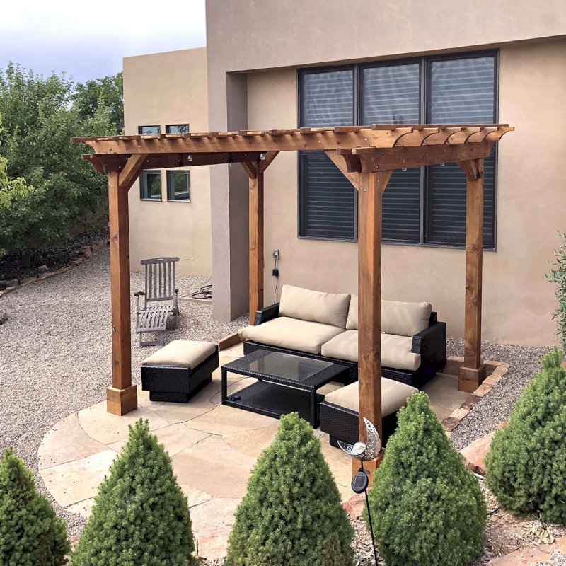 The Traditional Wooden Garden Pergola (Options: 12' L x 10' W, California Redwood, No Electrical Wiring Trim, Open Roof with Slats at 12", Rafters at 18", 4-Post Anchor Kit for Concrete, No Ceiling Fan Base, No Privacy Panels, No Curtain Rods, 9' Posts, Transparent Premium Sealant). Photo Courtesy of D. Johnson of Santa Fe, New Mexico. The Traditional Wooden Garden Pergola (Options: 12' L x 10' W, California Redwood, No Electrical Wiring Trim, Open Roof with Slats at 12", Rafters at 18", 4-Post Anchor Kit for Concrete, No Ceiling Fan Base, No Privacy Panels, No Curtain Rods, 9' Posts, Transparent Premium Sealant). Photo Courtesy of D. Johnson of Santa Fe, New Mexico.