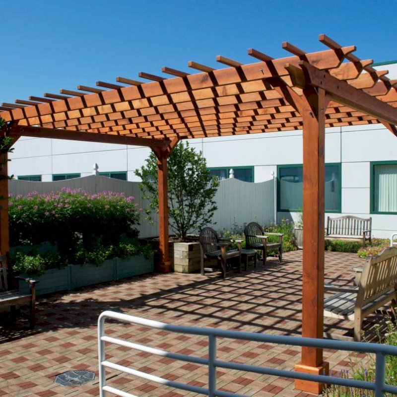 The Traditional Wooden Garden Pergola (Options: 18' L x 14' W, California Redwood, No Electrical Wiring Trim, Open Roof with Slats at 12", Rafters at 18", Widthwise Roof Support Timbers, 4-Post Anchor Kit For Stone, No Ceiling Fan Base, No Privacy Panels, No Curtain Rods, 9' Post Height, Transparent Premium Sealant). Photo Courtesy of Dartmouth Hitchcock Medical Center, Lebanon. The Traditional Wooden Garden Pergola (Options: 18' L x 14' W, California Redwood, No Electrical Wiring Trim, Open Roof with Slats at 12", Rafters at 18", Widthwise Roof Support Timbers, 4-Post Anchor Kit For Stone, No Ceiling Fan Base, No Privacy Panels, No Curtain Rods, 9' Post Height, Transparent Premium Sealant). Photo Courtesy of Dartmouth Hitchcock Medical Center, Lebanon.