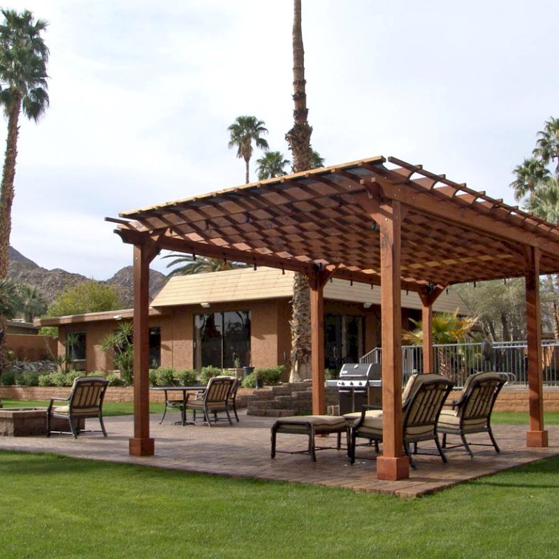 The Traditional Wooden Garden Pergola (Options: 26' L x 14' W, Mature Redwood, No Electrical Wiring Trim, Open Roof with Slats at 12", Rafters at 18", Lengthwise Roof Support Timbers, 6-Post Anchor Kit for Stone, No Ceiling Fan Base, No Privacy Panels, No Curtain Rods, 9' Post Height, Transparent Premium Sealant). Shade Cloth Added by Customer After Installation. Photo Courtesy of Val Kay of Indian Wells, CA. The Traditional Wooden Garden Pergola (Options: 26' L x 14' W, Mature Redwood, No Electrical Wiring Trim, Open Roof with Slats at 12", Rafters at 18", Lengthwise Roof Support Timbers, 6-Post Anchor Kit for Stone, No Ceiling Fan Base, No Privacy Panels, No Curtain Rods, 9' Post Height, Transparent Premium Sealant). Shade Cloth Added by Customer After Installation. Photo Courtesy of Val Kay of Indian Wells, CA.