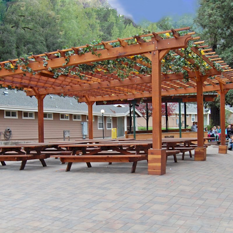 The Traditional Wooden Garden Pergola (Options: 30' L x 30' W, California Redwood, No Electrical Wiring Trim, Open Roof with Slats at 18", Rafters at 18", 6-Post Anchor Kit for Gale-Wind, No Ceiling Fan Base, No Privacy Panels, No Curtain Rods, 10' Post Height, Transparent Premium Sealant). After the tables and pavers were added. Picnic Tables are not Forever Redwood Tables. Photo Courtesy of Via West Campground located at 13851 Stevens Canyon Rd, Cupertino, CA. The Traditional Wooden Garden Pergola (Options: 30' L x 30' W, California Redwood, No Electrical Wiring Trim, Open Roof with Slats at 18", Rafters at 18", 6-Post Anchor Kit for Gale-Wind, No Ceiling Fan Base, No Privacy Panels, No Curtain Rods, 10' Post Height, Transparent Premium Sealant). After the tables and pavers were added. Picnic Tables are not Forever Redwood Tables. Photo Courtesy of Via West Campground located at 13851 Stevens Canyon Rd, Cupertino, CA.
