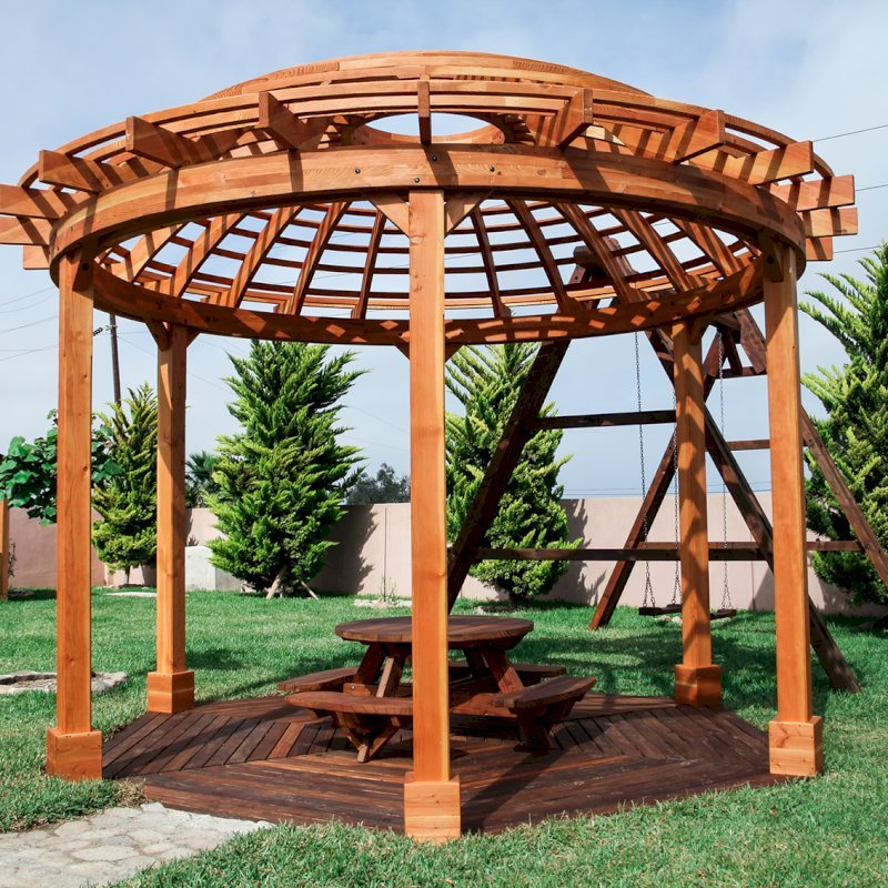 The Wooden Dome Pergola (Options: 16' Diameter, with Deck in Coffee Stain, Douglas-fir, Open Roof with Slats at 6", 9' Posts, No Electrical Wiring Trim, 6-Post Anchor Kit for Concrete, Transparent Premium Sealant). Photo Also shows a Round Picnic Table and a Rory's Swing Set in Background. The Wooden Dome Pergola (Options: 16' Diameter, with Deck in Coffee Stain, Douglas-fir, Open Roof with Slats at 6", 9' Posts, No Electrical Wiring Trim, 6-Post Anchor Kit for Concrete, Transparent Premium Sealant). Photo Also shows a Round Picnic Table and a Rory's Swing Set in Background.