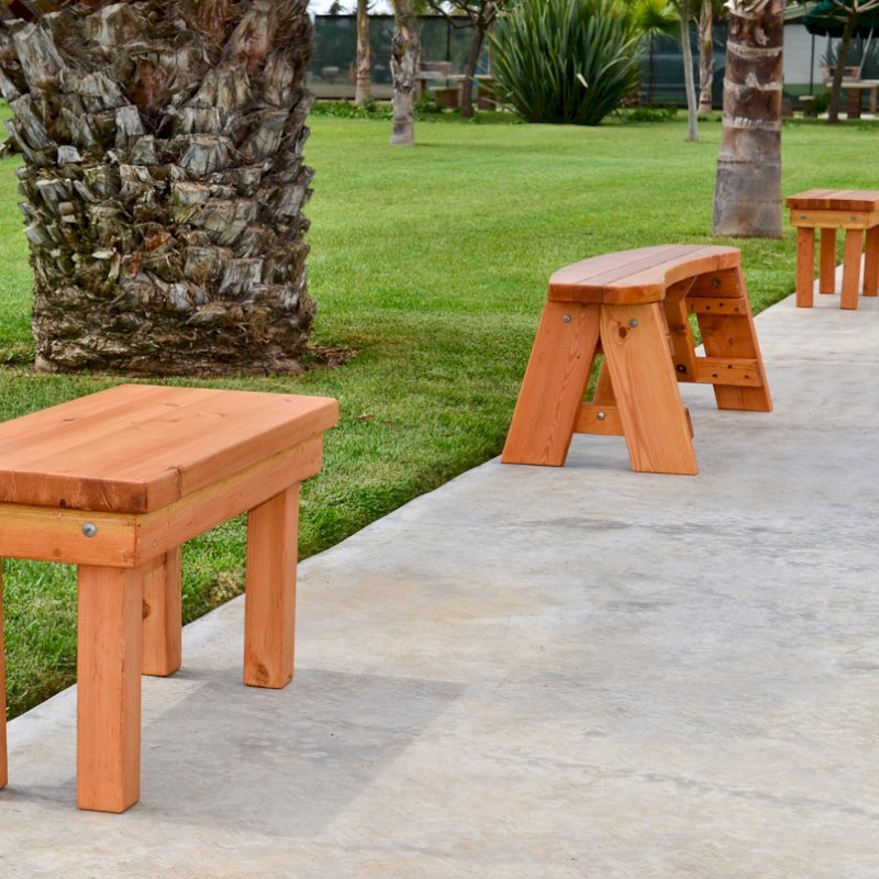 Wood Patio Bench (Options: 3 1/2 ft x 14 1/4 inches W x 18 1/2 inches H, Douglas-fir, No Cushion, No Engraving, Cherry Stain Premium Sealant). Photo also shows some round picnic benches. Wood Patio Bench (Options: 3 1/2 ft x 14 1/4 inches W x 18 1/2 inches H, Douglas-fir, No Cushion, No Engraving, Cherry Stain Premium Sealant). Photo also shows some round picnic benches.