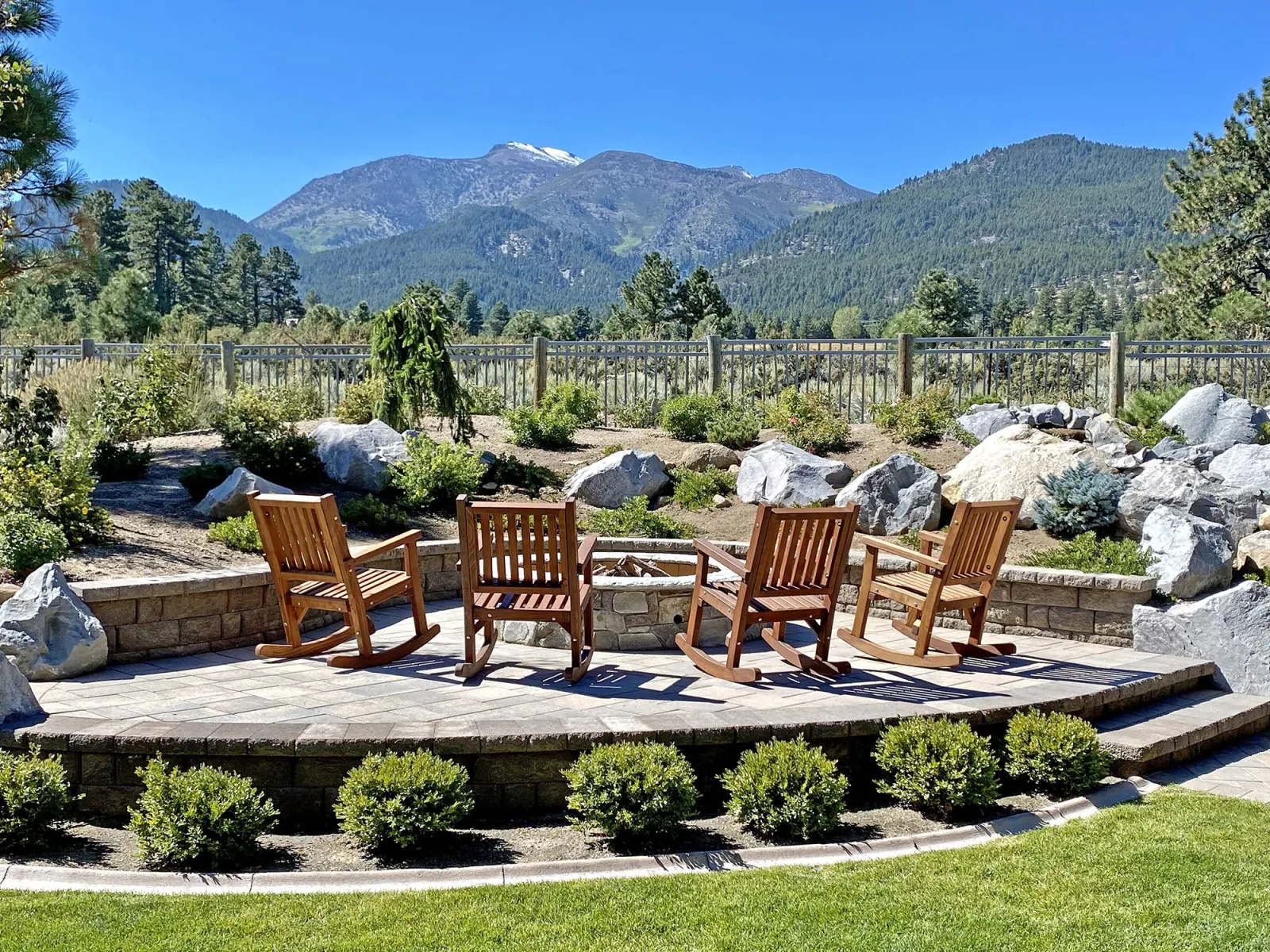 Sealed redwood rocking chairs around a fire pit with mountains behind