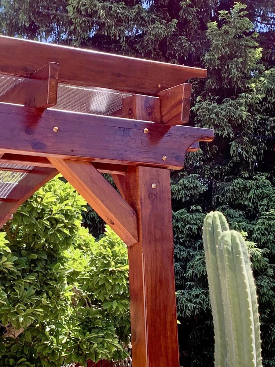 Arched Open Sky Pergolas (Options: 12' L x 14' Arc W, California Redwood, 1 Electrical Wiring Trim, 4-Post Anchor Kit for Concrete, No Ceiling Fan Base, No Privacy Panels, No Curtain Rods, 9.5' Post Height, Transparent Premium Sealant). Custom decorative steel shading added by customer. Photo was taken one year after installation. Photo Courtesy of K. Cates of Oajland, California.