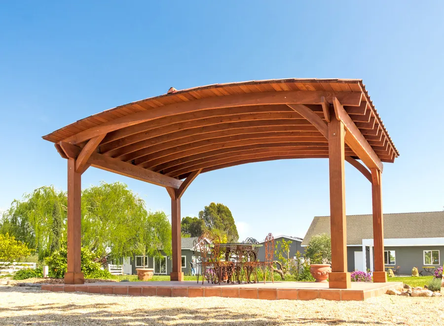Custom Arched Thick Timber Pavilion (Options: 14' L x 20' Arc W, Mature Redwood, 1 Electrical Wiring Trim, 4-Post Anchor Kit for Concrete, No Ceiling Fan Base, No Privacy Panel, No Curtain Rods, 9 ft H, with 2x6's Roof Boards by Custom Request, Coffee-Stain Premium Sealant). Photo Courtesy of Siino Ventures of Kikrland, Washington.