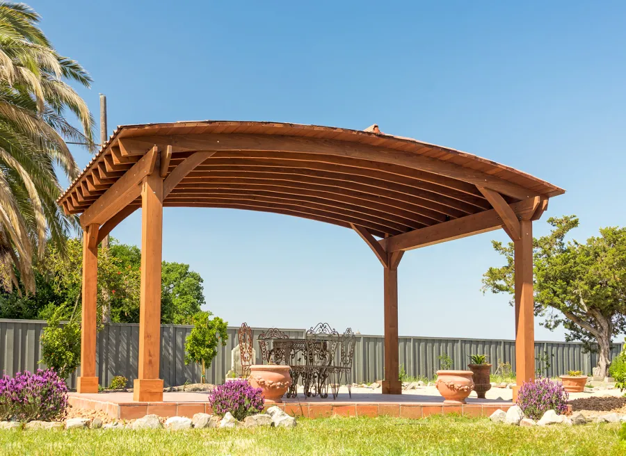 Custom Arched Thick Timber Pavilion (Options: 14' L x 20' Arc W, Mature Redwood, 1 Electrical Wiring Trim, 4-Post Anchor Kit for Concrete, No Ceiling Fan Base, No Privacy Panel, No Curtain Rods, 9 ft H, with 2x6's Roof Boards by Custom Request, Coffee-Stain Premium Sealant). Photo Courtesy of Siino Ventures of Kikrland, Washington.