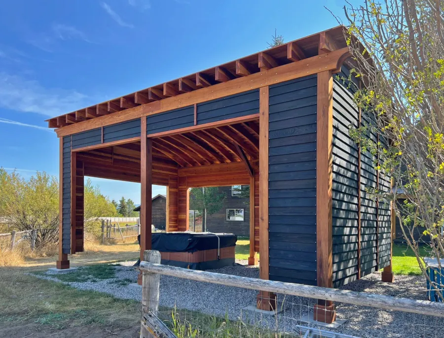 Custom  Arched Thick Timber Pavilion (Options: 28' L x 18' Arc W, California Redwood, Post Anchor Kit for High-Wind, with Custom Privacy Walls, 10' & 12' H Posts, No Curtain Rods, Walls Siding with Black Stain and the Rest of the Structure with Transparent Premium Sealant). Photo Courtesy of D. Harris of Tetonia, ID.