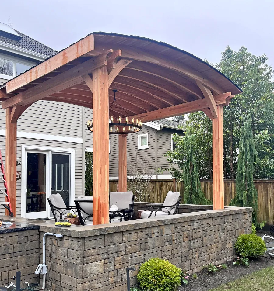  Arched Thick Timber Pavilion (Options: 14' L x 14' Arc W, Mosaic Douglas-fir, 2 Electrical Wiring Trims, 4-Post Anchor Kit for High-Wind, 1 Ceiling Fan Base, 11' H Posts, No Privacy Panel, No Curtain Rods, 12 ft H, No Decorative Trims on Posts, Unfinished). Photo Taken Before Gutters Were Installed. Photo Courtesy of K. Bachman-Ellis of Bellevue, WA.