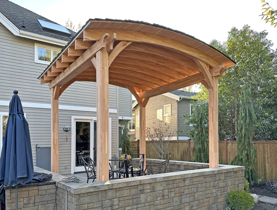  Arched Thick Timber Pavilion (Options: 14' L x 14' Arc W, Mosaic Douglas-fir, 2 Electrical Wiring Trims, 4-Post Anchor Kit for High-Wind, 1 Ceiling Fan Base, 11' H Posts, No Privacy Panel, No Curtain Rods, 12 ft H, No Decorative Trims on Posts, Unfinished). Photo Courtesy of K. Bachman-Ellis of Bellevue, WA.
