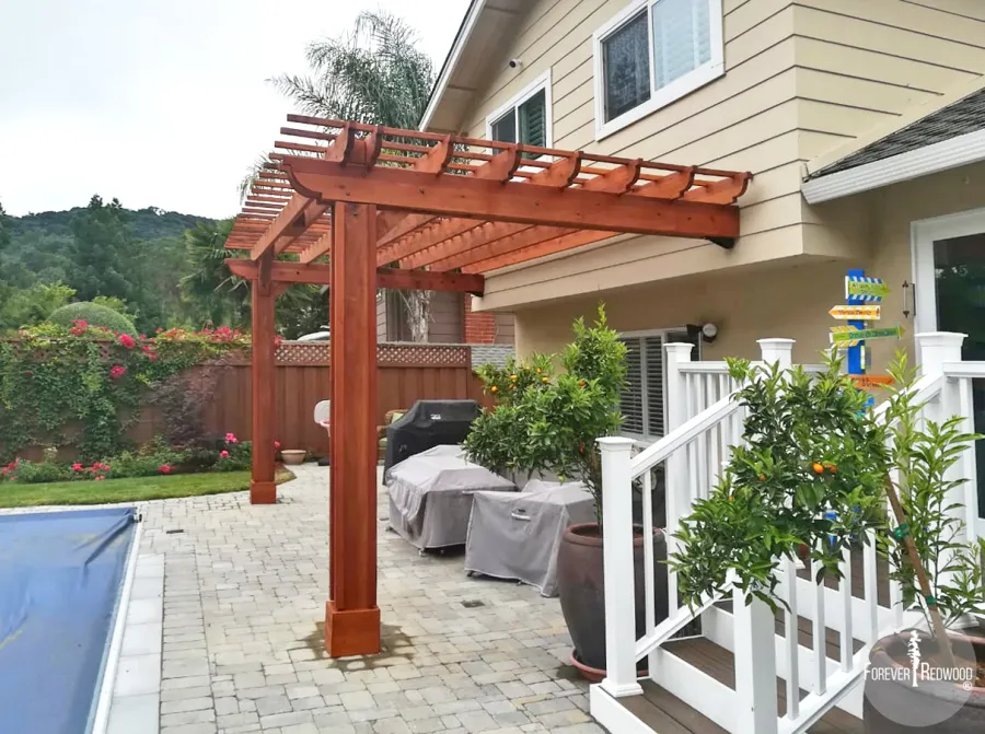 Attached Garden Pergolas (Options: 20' L x 10' W, Mature Redwood, No Electrical Wiring Trim, 2-Post Anchor Kit for High-Wind, Open Roof with Slats at 12", Rafters at 18", Vertical post decorative trim, Transparent Premium Sealant). Photo Courtesy of D. Abrams of San Jose, California.