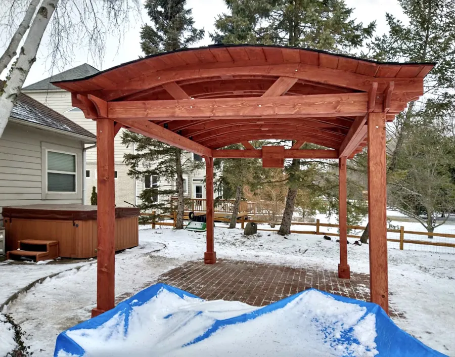 Custom Backyard Pavilion Kit with Extra Supports and Braces on Arches Side (Options: 16' L x 12' Arc W, Douglas-fir, 1 Post Electrical Wiring Trim, 4-Post Anchor Kit for High-Wind, 1 TV Mount Base by Custom Request, No Privacy Panels, No Curtain Rods, 9 ft Post Height, Cherry-Stain Premium Sealant). Photo Courtesy of E. Chen of Ann Arbor, Michigan.