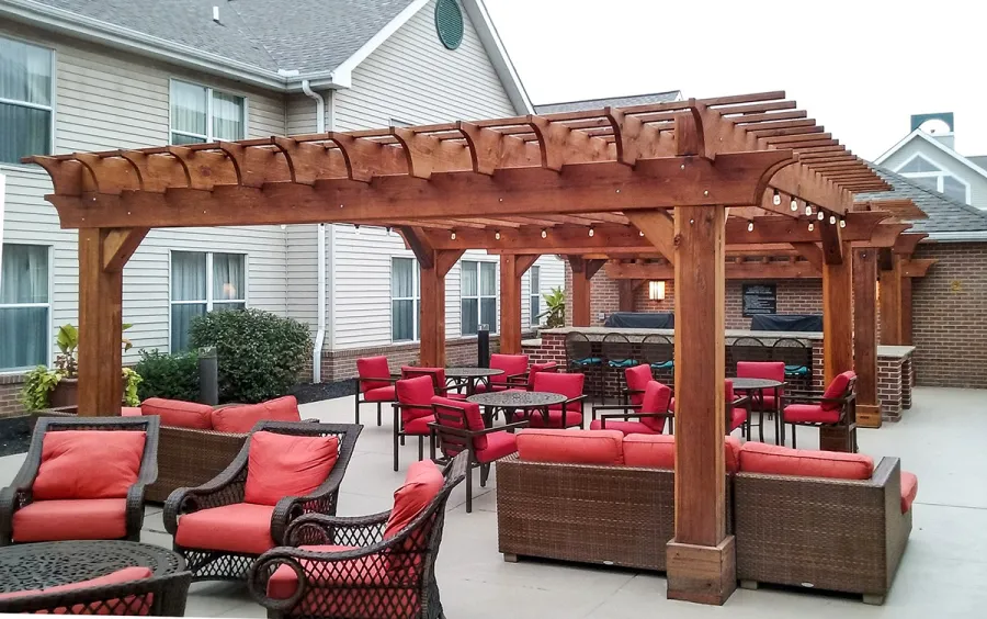 Custom Wooden Fat Timber Pergola (Options: 20' x 20', California Redwood, Electrical Wiring Trim for 1 Post, Open Roof with Rafters at 18", Slats at 12", 4-Post Anchor Kit for Concrete, No Ceiling Fan Bases, No Privacy Panels, No Curtain Rods, Transparent Premium Sealant). Thicker Lumber by Custom Request, 2 x 12 Rafters & Supports, 10 x10 Posts. Photo Courtesy of Homewood Suites by Hilton, Mechanicsburg, PA.