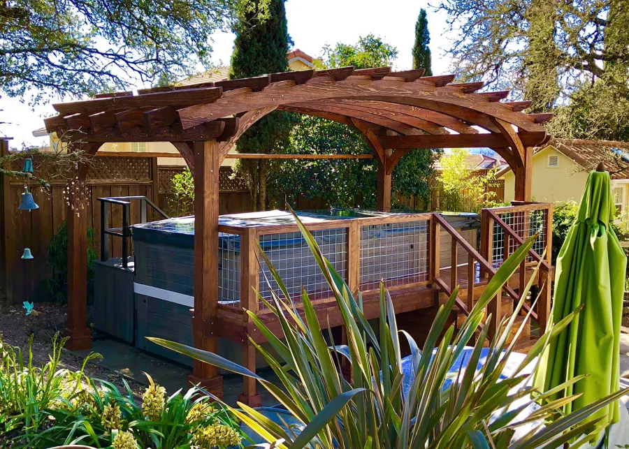 Custom Arched Pergola Kits (Options: 12' L x 22' Arc W, Douglas-fir, Unattached, Electrical Wiring Trim Kit for 1 Post, Arched Roof with Lattice Panels and Acrylic Sheets Centered, 4-Post Anchor Kit for Stone, with 8 x 8 Posts by Custom Request, No Ceiling Fan Base, No Privacy Panels, 1 Curtain Rod, 9' Post Height, Coffee-Stain Premium Sealant) with Custom Deck and Stairs by Custom Request. Photo Courtesy of Steve & Heidi Jones of Windsor, CA.
